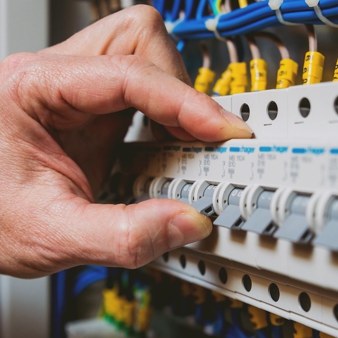 A control board with an electrician's hand coming in to adjust the components.