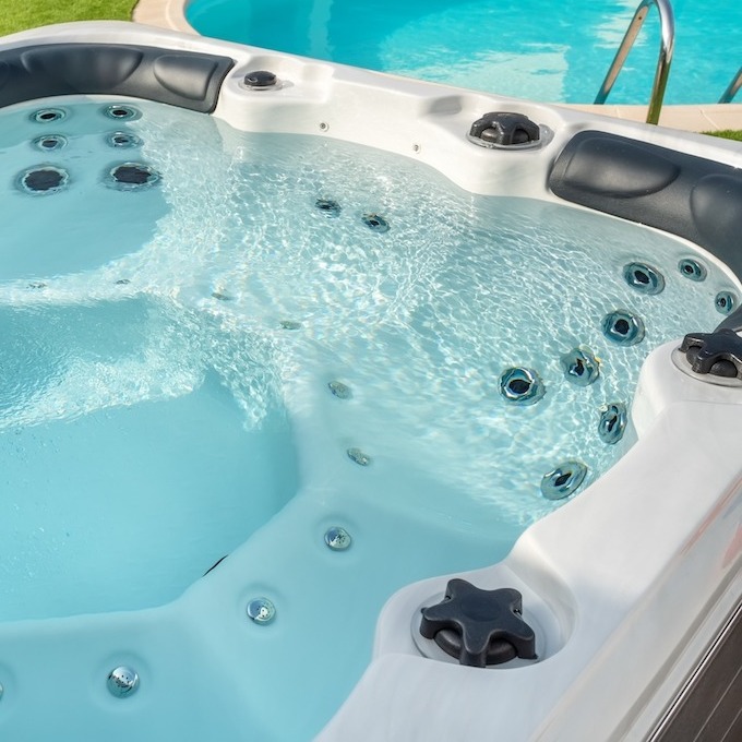 A brand-new hot tub with a pool in the background.